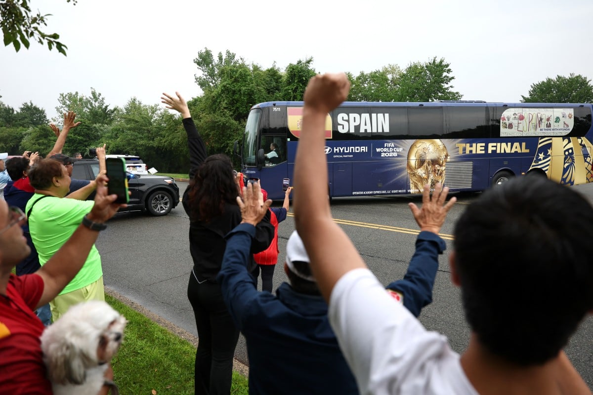 Aficionados españoles saludan y toman fotos mientras el autobús del equipo parte tras la cancelación de su entrenamiento debido a las condiciones meteorológica.
