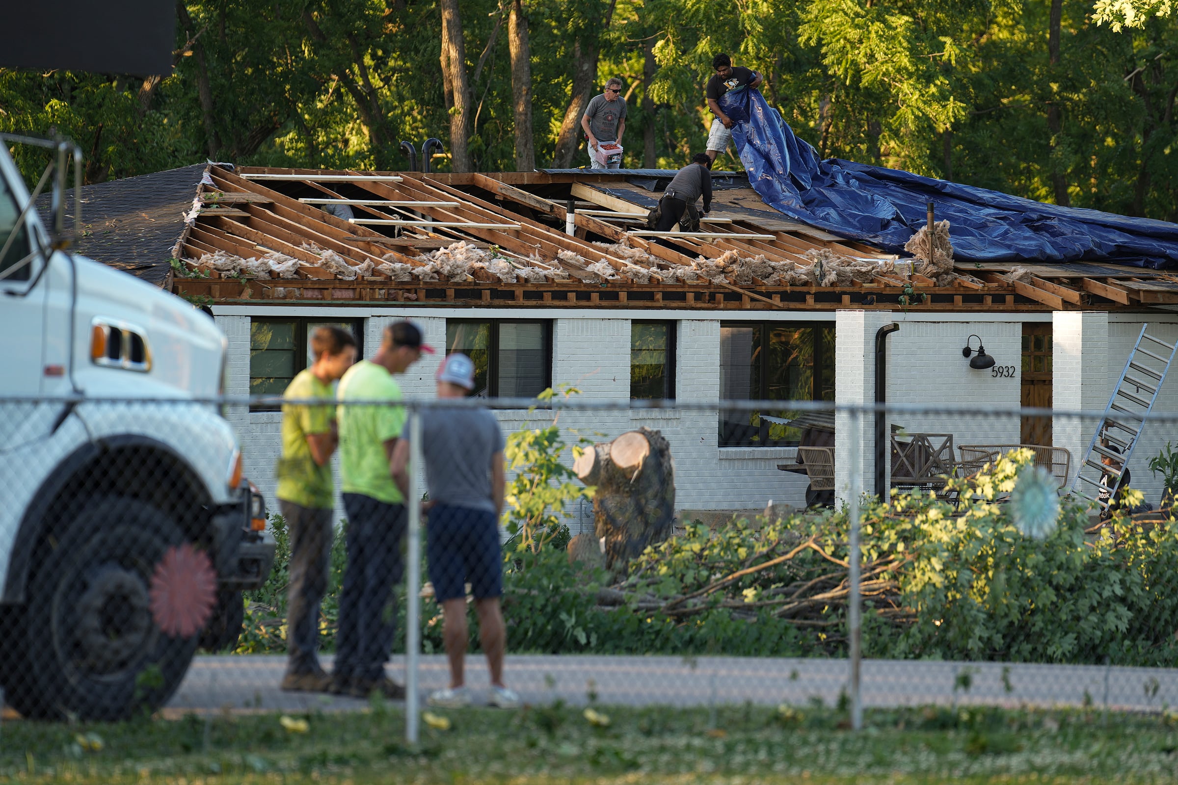 Los trabajadores se afanan para poner una lona sobre un techo dañado después de que un tornado azotara varias áreas de Greenwood, Indiana