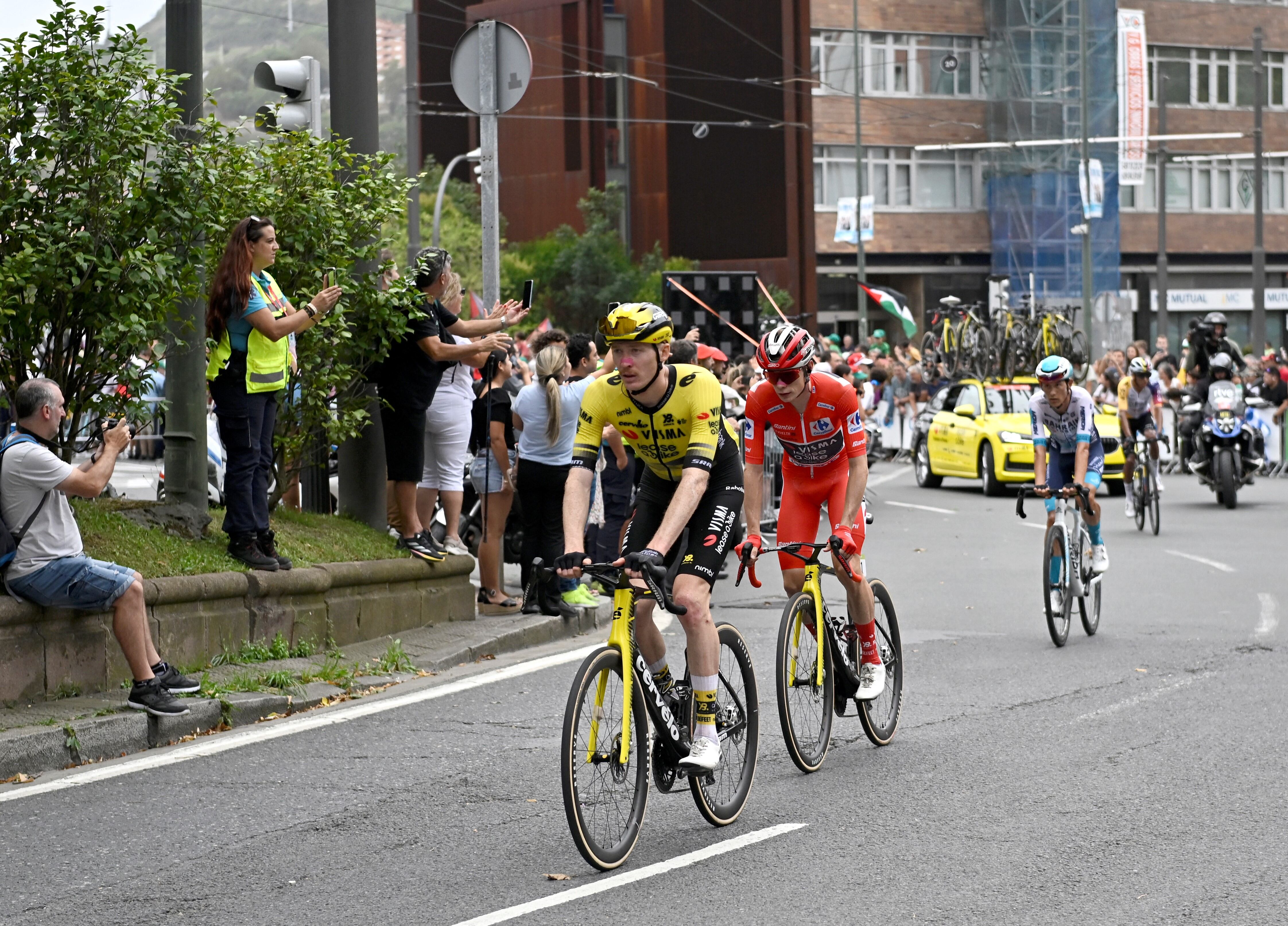 The overall leader Team Visma-Lease a bike's Danish rider Jonas Vingegaard (2L) rides back to his bus as Pro-Palestinian protesters demonstrate at the finish line during the Vuelta 11th stage, in Bilbao, on September 3, 2025. Pro-Palestinian protest forces Vuelta stage to be shortened and to take the time at 3 kms before the line, according to the organisers, AFP reports. (Photo by ANDER GILLENEA / AFP)