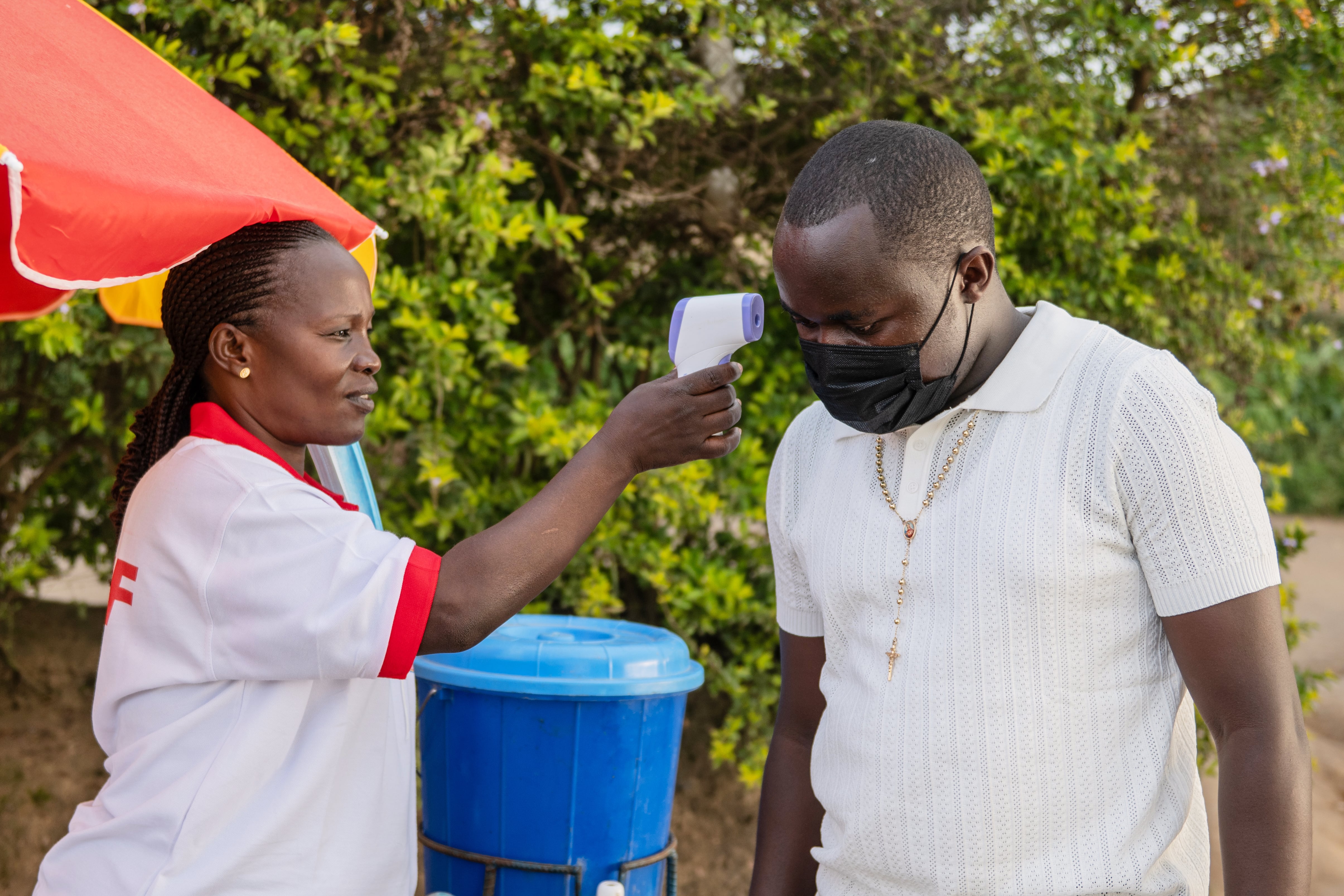 Un trabajador de la salud utiliza un termómetro para examinar a un hombre al borde de la carretera en Bunia, Congo, el martes 19 de mayo de 2026. (Foto AP/Moses Sawasawa)