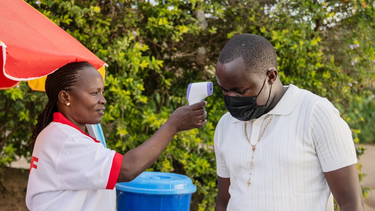 Un trabajador de la salud utiliza un termómetro para examinar a un hombre al borde de la carretera en Bunia, Congo, el martes 19 de mayo de 2026. (Foto AP/Moses Sawasawa)