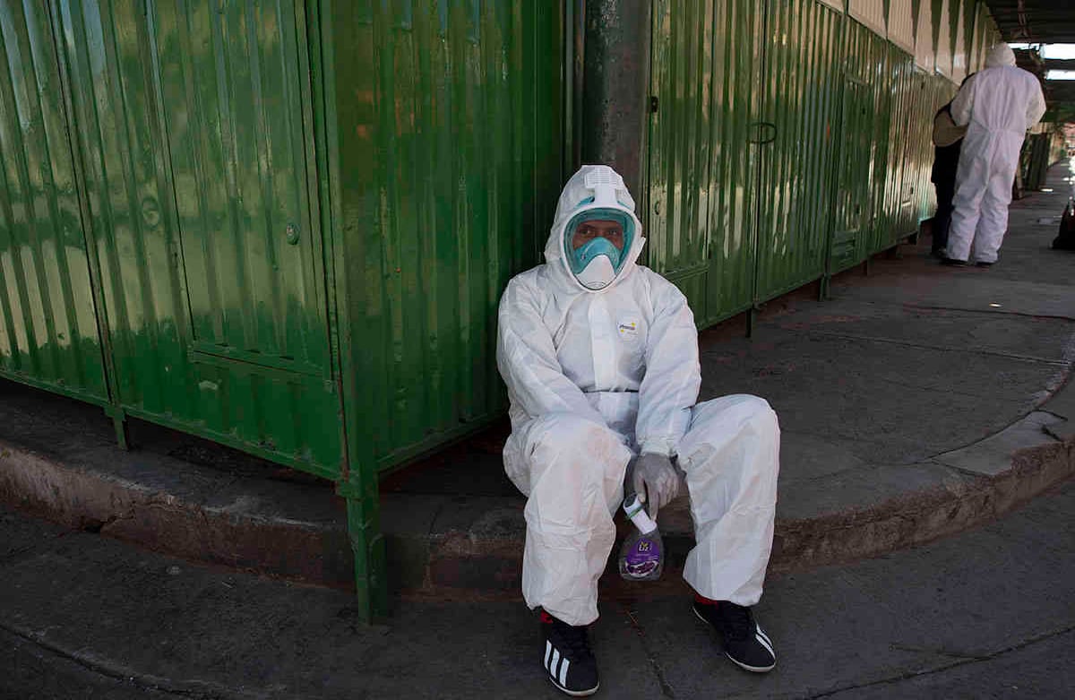 Un trabajador de la salud vestido con equipo de protección completo toma un descanso durante una nueva prueba de coronavirus de casa en casa, en el barrio de Villa Dolores de El Alto, Bolivia, el sábado 18 de julio de 2020. (Foto AP / Juan Karita)