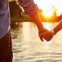 Pareja cogidos de la mano junto al río. Amor, enamorados.