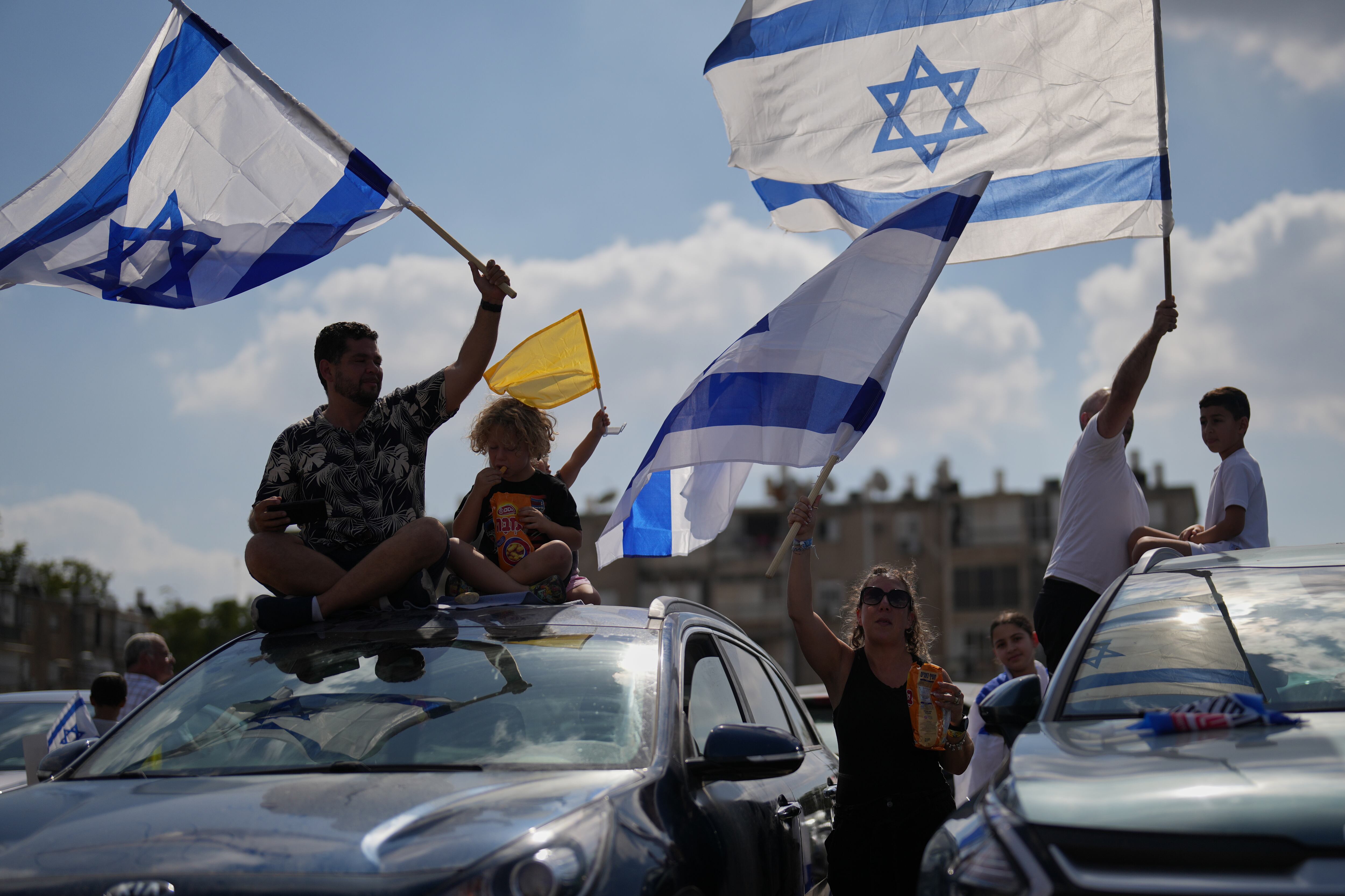 La gente ondea banderas israelíes en señal de celebración mientras esperan afuera del Hospital Beilinson en Petah Tikva, Israel, la llegada de algunos de los secuestrados liberados.