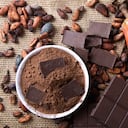 Detalle de frutos de cacao con trozos de chocolate y cacao en polvo sobre granos de cacao crudos.