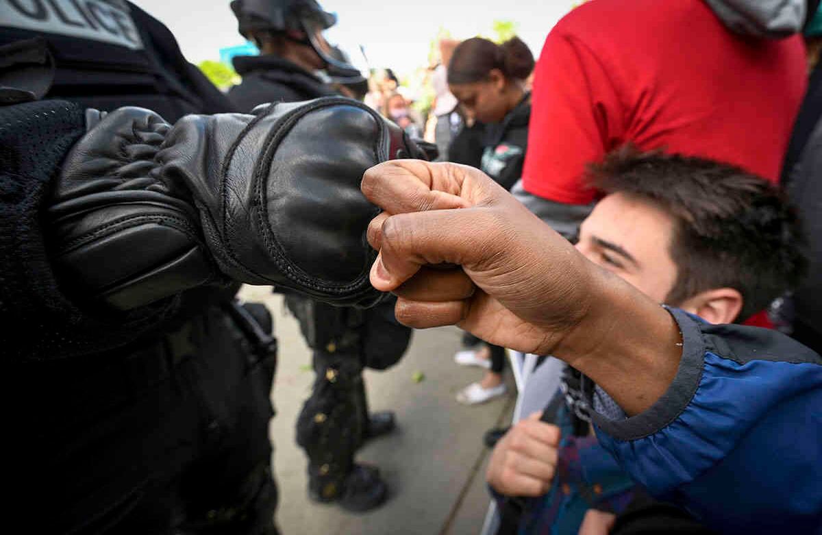 "El respeto va en ambos sentidos", dice un manifestante llamado Monique que junta su puño con el de un oficial de la policía de Spokane, vestido con equipo antidisturbios, frente al Palacio de Justicia del Condado de Spokane el domingo 31 de mayo de 2020. Foto: Colin Mulvany / The Spokesman-Review vía AP.