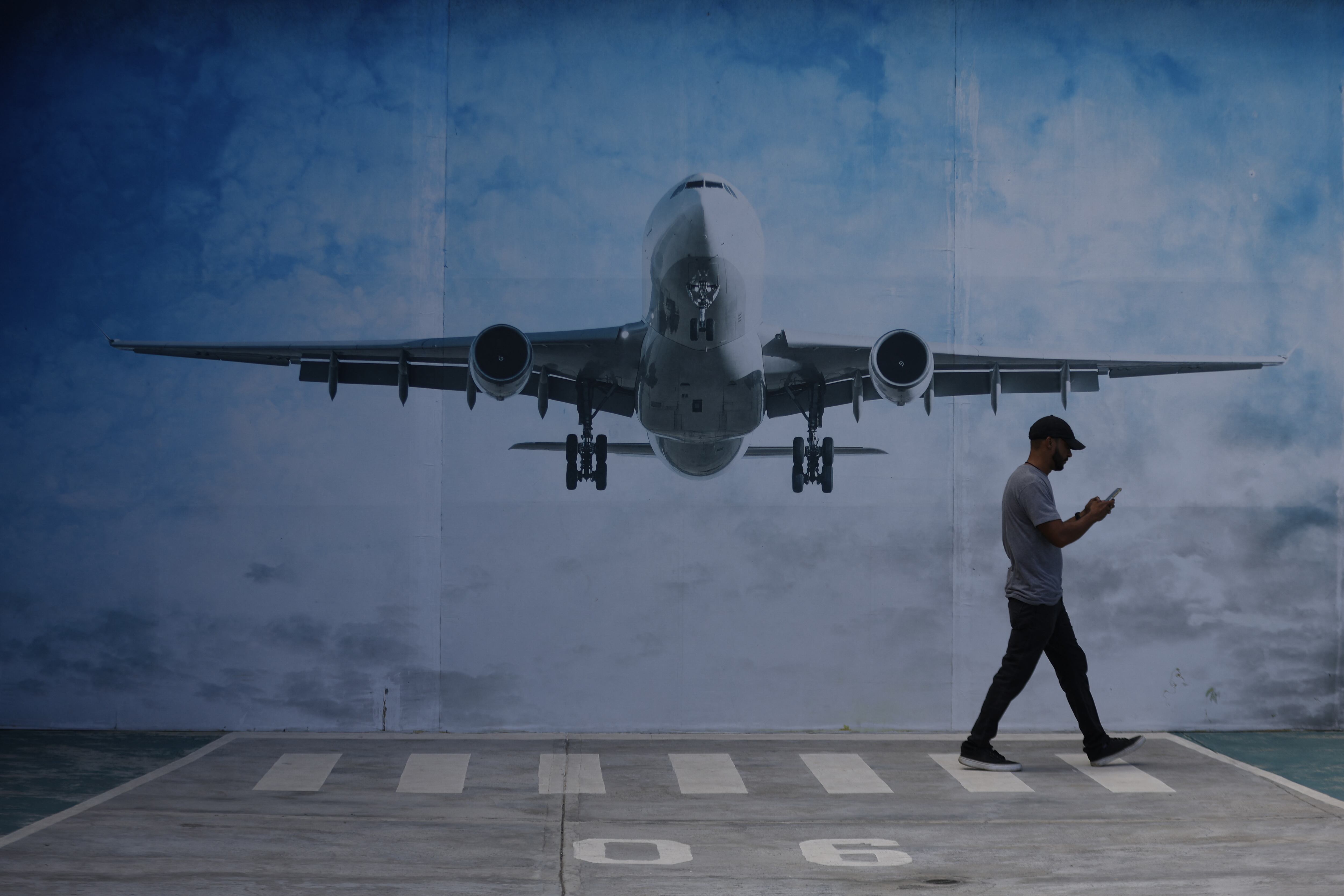 LA GUAIRA, VENEZUELA - NOVEMBER 30: A man walks next to a mural of an airplane in La Guaira State, Venezuela, on November 30, 2025. US President Donald Trump significantly escalated his threats against Venezuela on Saturday with an ominous warning that the country's airspace should be considered “closed,�? raising fears of imminent military action. Pedro Mattey / Anadolu (Photo by Pedro Mattey / Anadolu via AFP)
