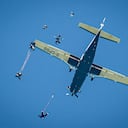 Los paracaídas se despliegan después de la caída libre debajo de un avión Cessna