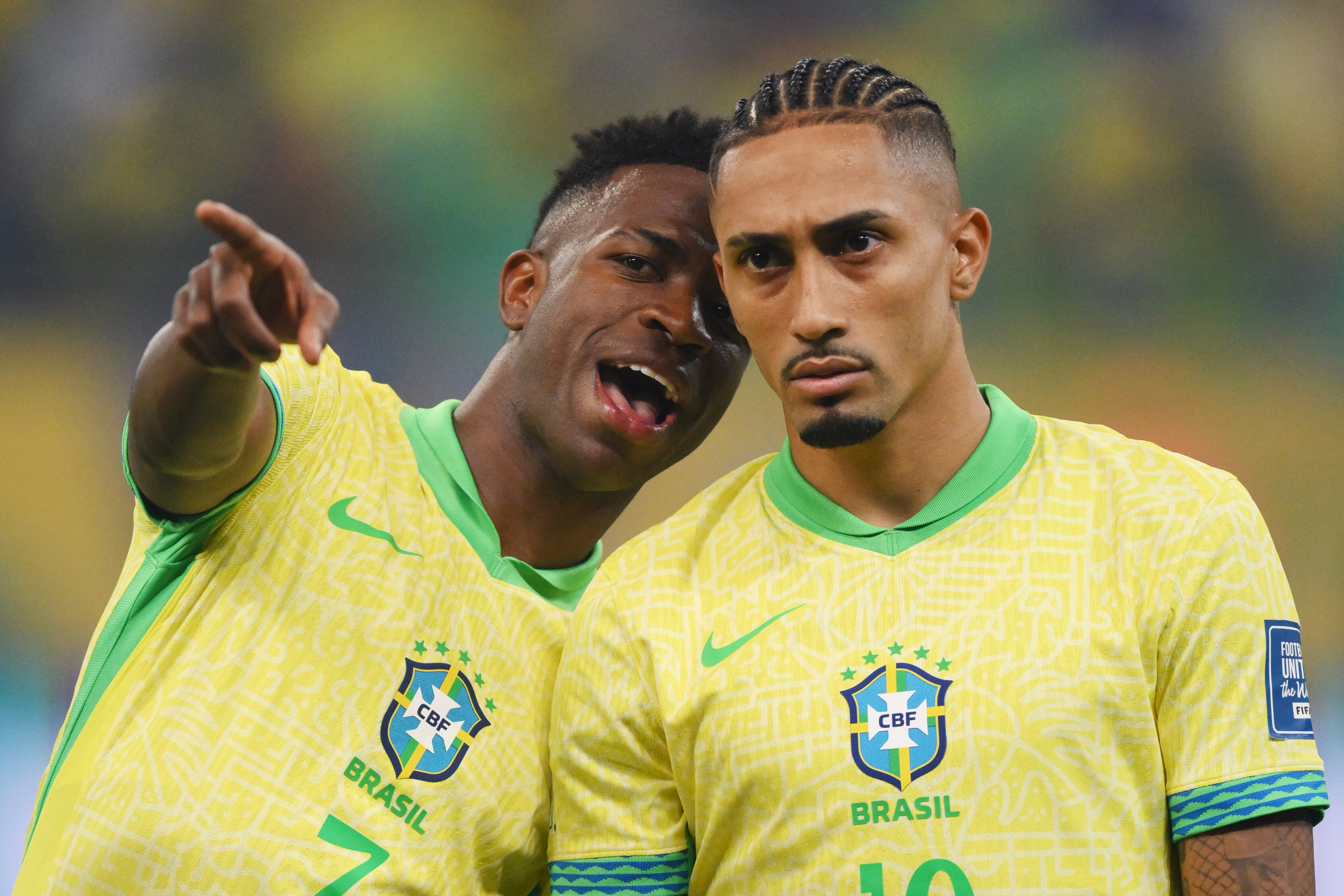 SALVADOR, BRAZIL - NOVEMBER 19: Vinicius Junior and Raphinha of Brazil talk as they line up prior to the South American FIFA World Cup 2026 Qualifier match between Brazil and Uruguay at Arena Fonte Nova on November 19, 2024 in Salvador, Brazil. (Photo by Pedro Vilela/Getty Images)