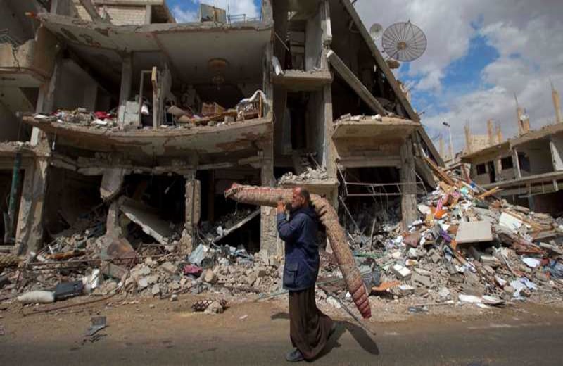 Un hombre sirio carga una alfombra mientras pasa por un segmento devastado de la ciudad ancestral de Palmira. Los ciudadanos están volviendo a esta población luego de que el ejército por fin pudo expulsar al Estado Islámico. 