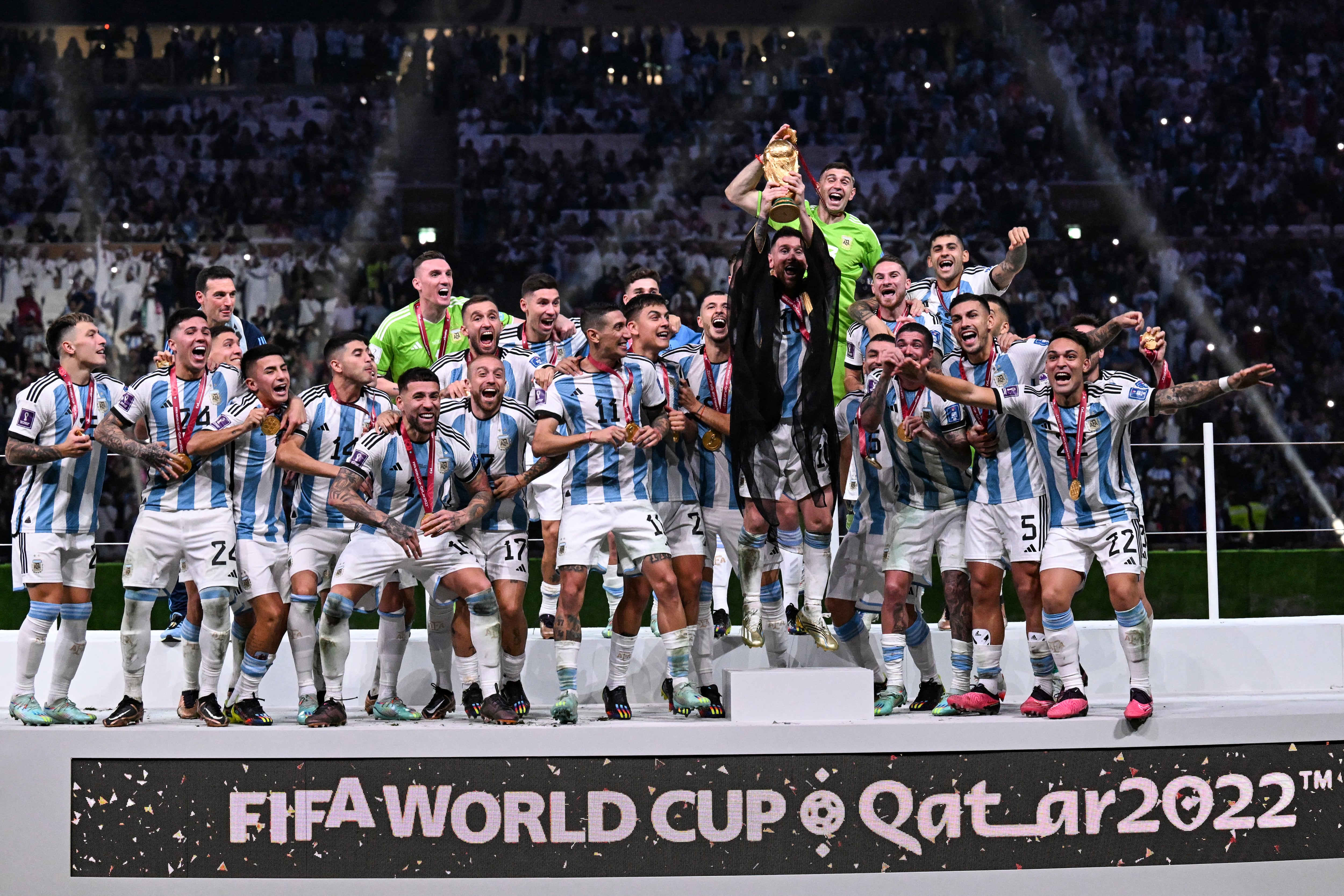 El delantero argentino Lionel Messi (centro) sostiene el trofeo de la Copa Mundial de la FIFA mientras celebra con sus compañeros la victoria en la final de la Copa Mundial de Qatar 2022 entre Argentina y Francia en el estadio Lusail, al norte de Doha, el 18 de diciembre de 2022. (Foto de Kirill KUDRYAVTSEV / AFP)