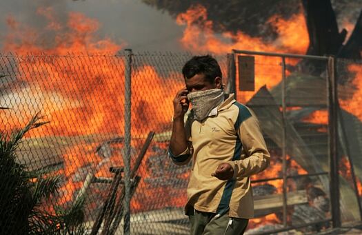 Un hombre camina por una yarda ardiente en Dioni, al este de Atenas, Grecia, lunes 24 de agosto de 2009.
