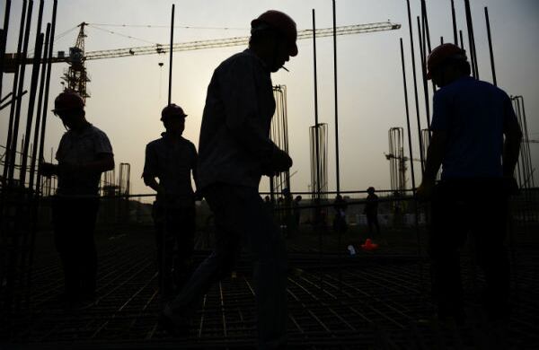 En esta fotografía, se siluetean a unos trabajadores que trabajan en la construcción de un sitio residencial en la provincia de Shandong, China. (AP)