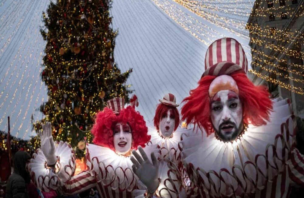Vestidos con rayas blancas y rojas, artistas dibujan gestos en sus rostros mientras posan junto al decorado de año nuevo y las celebraciones de navidad ortodoxa en Moscú, Rusia, en el mercado de vacaciones cerca de la Plaza Roja. Lunes,  30 de diciembre de 2019. Foto: Alexander Zemlianichenko/ AP. 