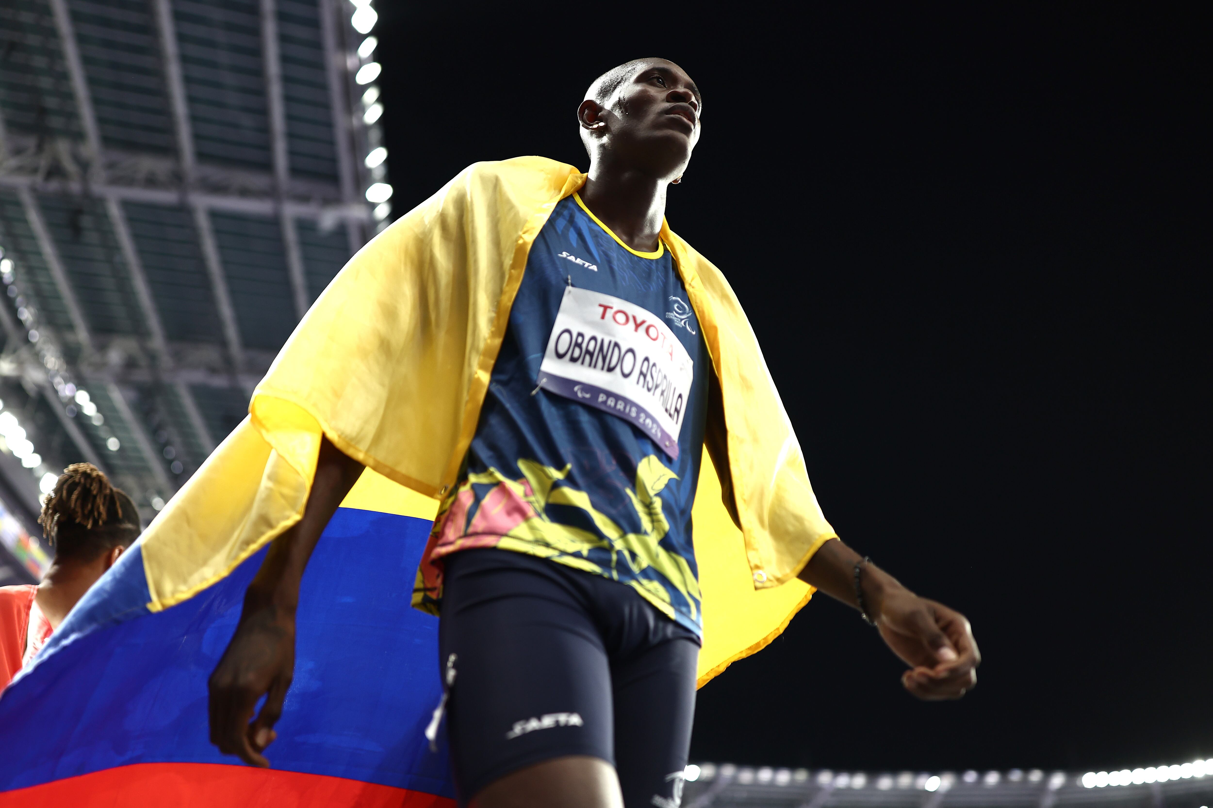 PARIS, FRANCE - SEPTEMBER 03: Jhon Sebastian Obando Asprilla of Team Colombia poses for a photo with a Colombia flag after winning gold during the Men's 400m T20 Final on day six of the Paris 2024 Summer Paralympic Games at Stade de France on September 03, 2024 in Paris, France. (Photo by Naomi Baker/Getty Images)