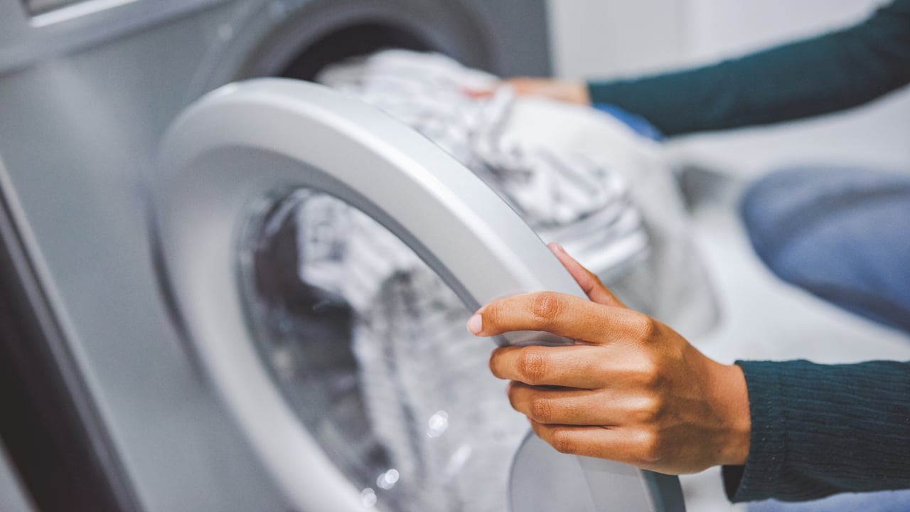 Closeup shot of an unrecognisable woman using a washing machine to do laundry at home