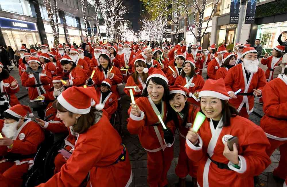Los empleados de la tienda Marunouchi y los trabajadores que visten los trajes de Santa Claus se unen a un desfile de Navidad en el distrito comercial de Marunouchi en Tokio el 22 de diciembre de 2017. Foto: AFP / Toshifumi KITAMURA