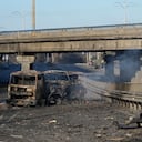 A Ukrainian soldier investigates debris of a burnt military truck in a street in Kyiv, Ukraine, Saturday, Feb. 26, 2022. Russian troops stormed toward Ukraine's capital Saturday, and street fighting broke out as city officials urged residents to take shelter. (AP Photo/Efrem Lukatsky)