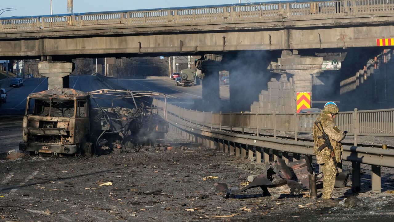 A Ukrainian soldier investigates debris of a burnt military truck in a street in Kyiv, Ukraine, Saturday, Feb. 26, 2022. Russian troops stormed toward Ukraine's capital Saturday, and street fighting broke out as city officials urged residents to take shelter. (AP Photo/Efrem Lukatsky)