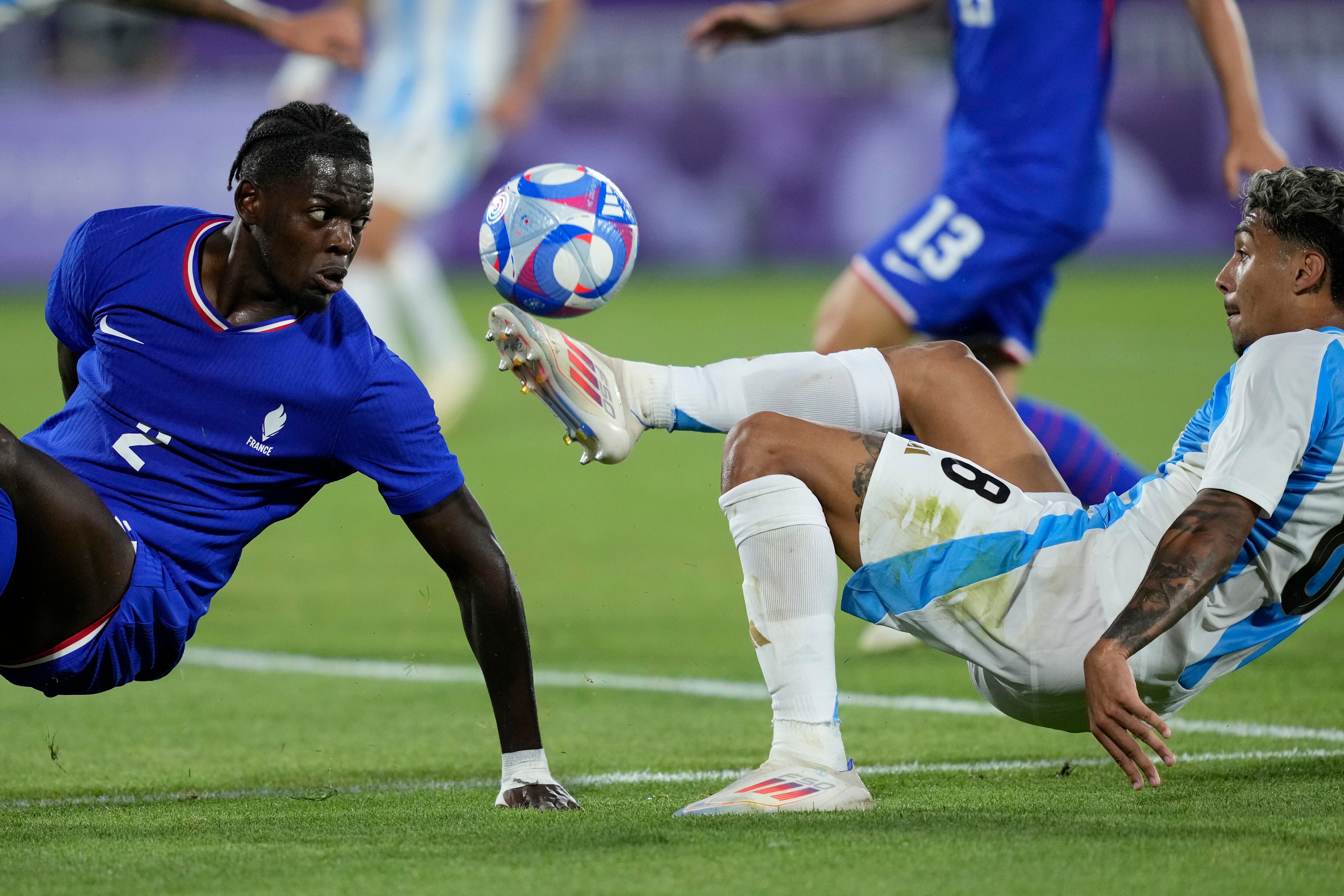 El francés Adrien Truffert salta sobre el portero argentino Geronimo Rulli durante un partido de fútbol de cuartos de final entre Francia y Argentina, en el estadio de Burdeos, durante los Juegos Olímpicos de verano de 2024, el viernes 2 de agosto de 2024, en Burdeos, Francia. (Foto AP/Rebecca Blackwell)