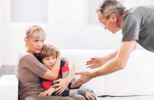 Mature father is scolding his son while mother is defending him.