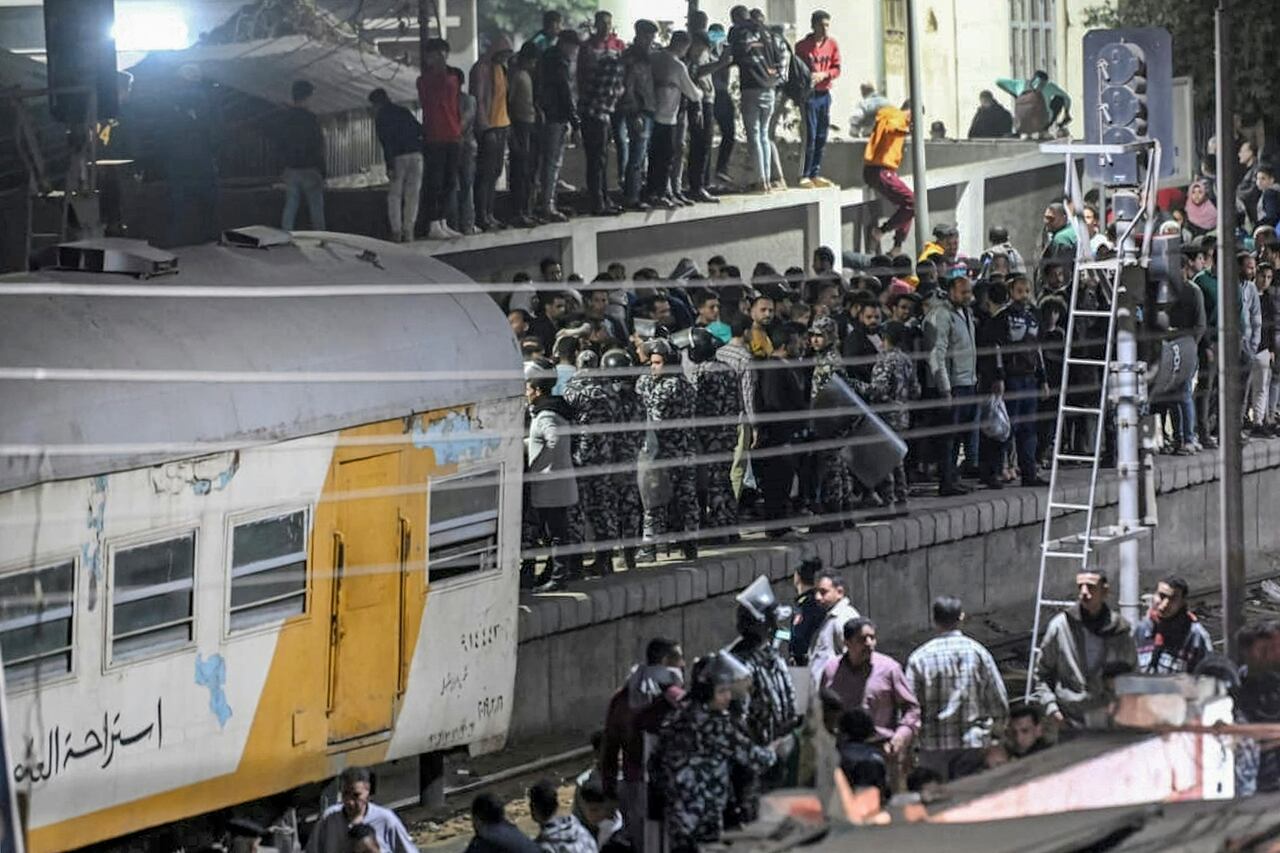 Policías forman un perímetro mientras la gente se reúne en la escena de un accidente de tren en la ciudad de Qalyub, en la provincia de Qalyub, en la región egipcia del delta del Nilo, al norte de la capital, el 7 de marzo de 2023. (Foto de Khaled KAMEL / AFP)