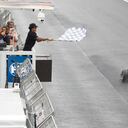 El piloto de Red Bull, Max Verstappen, de los Países Bajos, recibe la bandera a cuadros ondeada por el surfista brasileño Gabriel Medina para ganar el Gran Premio de Brasil de Fórmula 1 en la pista de carreras Interlagos en Sao Paulo, Brasil, el domingo 3 de noviembre de 2022. (Sebastian Moreira/Pool vía AP)