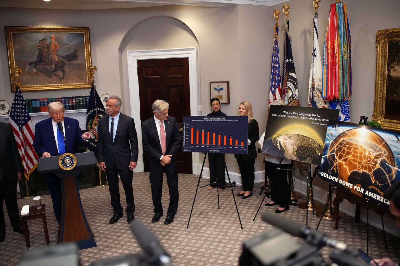 El presidente de EE. UU., Donald Trump (izq.), acompañado por el secretario de Servicios Humanos, Robert F. Kennedy Jr. (centro), y el administrador de los Centros de Servicios de Medicare y Medicaid (CMS), Mehmet Oz, señala carteles sobre el sistema de defensa antimisiles Golden Dome durante una conferencia de prensa en la Sala Roosevelt de la Casa Blanca el 12 de mayo de 2025