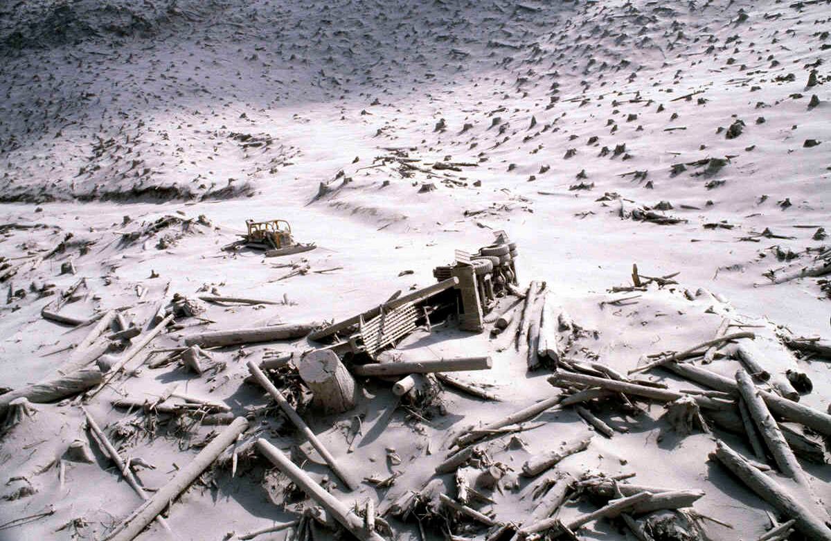 En esta foto de archivo del 20 de mayo de 1980, un camión de troncos destrozado y un tractor de orugas se muestran en medio de cenizas y árboles caídos cerca del Monte St. Helens dos días después de la erupción del volcán en el estado de Washington. El 18 de mayo de 2020 es el 40 aniversario de la erupción. Foto AP / Archivo
