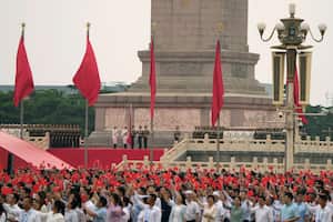 Miembros del partido comunista agitan banderas mientras una guardia de honor se prepara para izar la bandera nacional durante una ceremonia para conmemorar el centenario de la fundación del gobernante Partido Comunista Chino en la Puerta de Tiananmen en Pekín el jueves 1 de julio de 2021. Foto: AP Photo/Ng Han Guan.