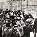 Jewish children, survivors of Auschwitz, with a nurse behind a barbed wire fence, Poland, February 1945. Photo taken by a Russian photographer during the making of a film about the liberation of the camp. The children were dressed up by the Russians with clothing from adult prisoners. (Photo by Galerie Bilderwelt/Getty Images)