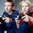 dos niños de 10 y 13 años jugando con videoconsolas.