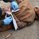 Contenido gráfico / Un trabajador comunal libera las muñecas de un hombre muerto, con las manos atadas a la espalda, en la ciudad de Bucha, no lejos de la capital ucraniana, Kiev, el 3 de abril de 2022. - El presidente Volodymyr Zelensky acusó a Rusia de cometer genocidio e intentar eliminar a "toda la nación" de Ucrania, un día después del descubrimiento de fosas comunes y civiles aparentemente ejecutados cerca de Kiev. Ucrania recuperó 410 cuerpos de civiles de áreas que recientemente recuperó del ejército ruso en la región más amplia de Kiev, dijo el domingo su fiscal general Iryna Venediktova. (Photo by Sergei SUPINSKY / AFP)