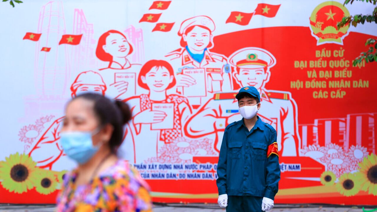 A masked security person guards outside a polling station in Hanoi, Vietnam Sunday, May 23, 2021. Vietnamese cast their ballots to elect 500 delegates for a five-year term at the National Assembly, Vietnam's legislative body, as the country is combating a new wave of COVID-19. (AP Photo/Hau Dinh)