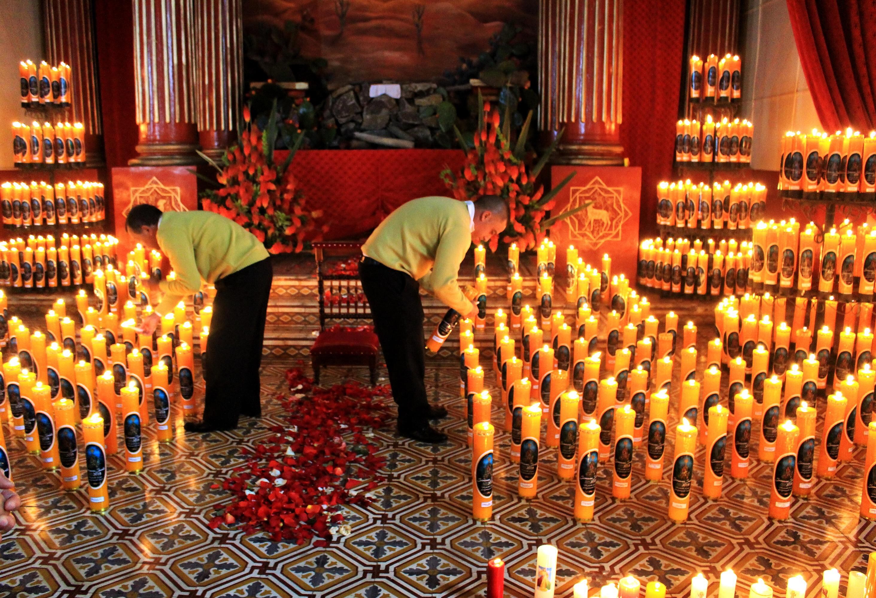 Dos mujeres encienden las velas de los feligreses en la iglesia de Silvia, Cauca, el Jueves Santo. (Foto: Bernardo Peña)