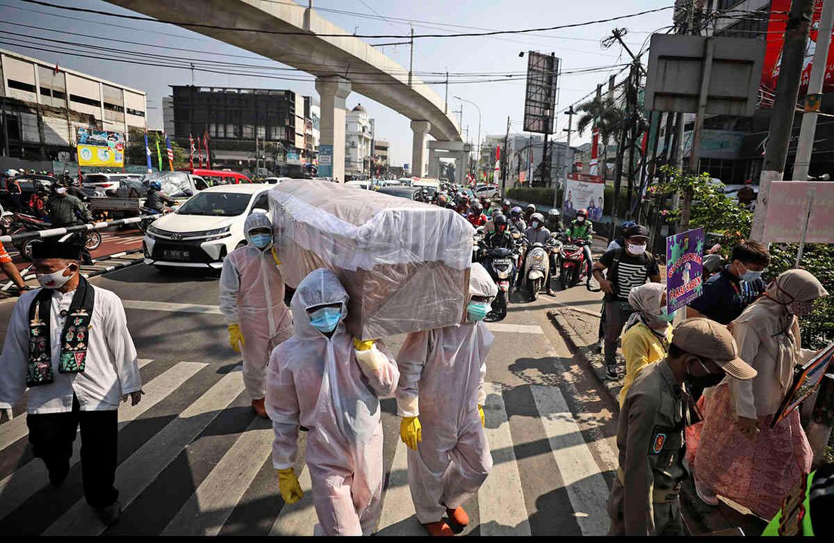 Los funcionarios del gobierno en Indonesia llevan un ataúd simulado mientras caminan por una intersección concurrida durante una campaña de concientización sobre el coronavirus, con el fin de recordar a las personas el riesgo de contraer Covid-19 y la necesidad de obedecer los protocolos de salud para frenar la propagación del brote en Yakarta. Foto: Dita Alangkara / AP 