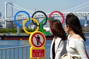 Women walk by a "no trespassing" sign at a park with a backdrop of the Olympic rings floating in the water in the Odaiba section Thursday, March 18, 2021, in Tokyo. Tokyo Olympics creative director Hiroshi Sasaki is resigning after making demeaning comments about Naomi Watanabe, a well-known female celebrity. Sasaki who was in charge of the opening and closing ceremonies for the Olympics, told planning staff members last year that Watanabe could perform in the ceremony as an “Olympig.” (AP Photo/Eugene Hoshiko)