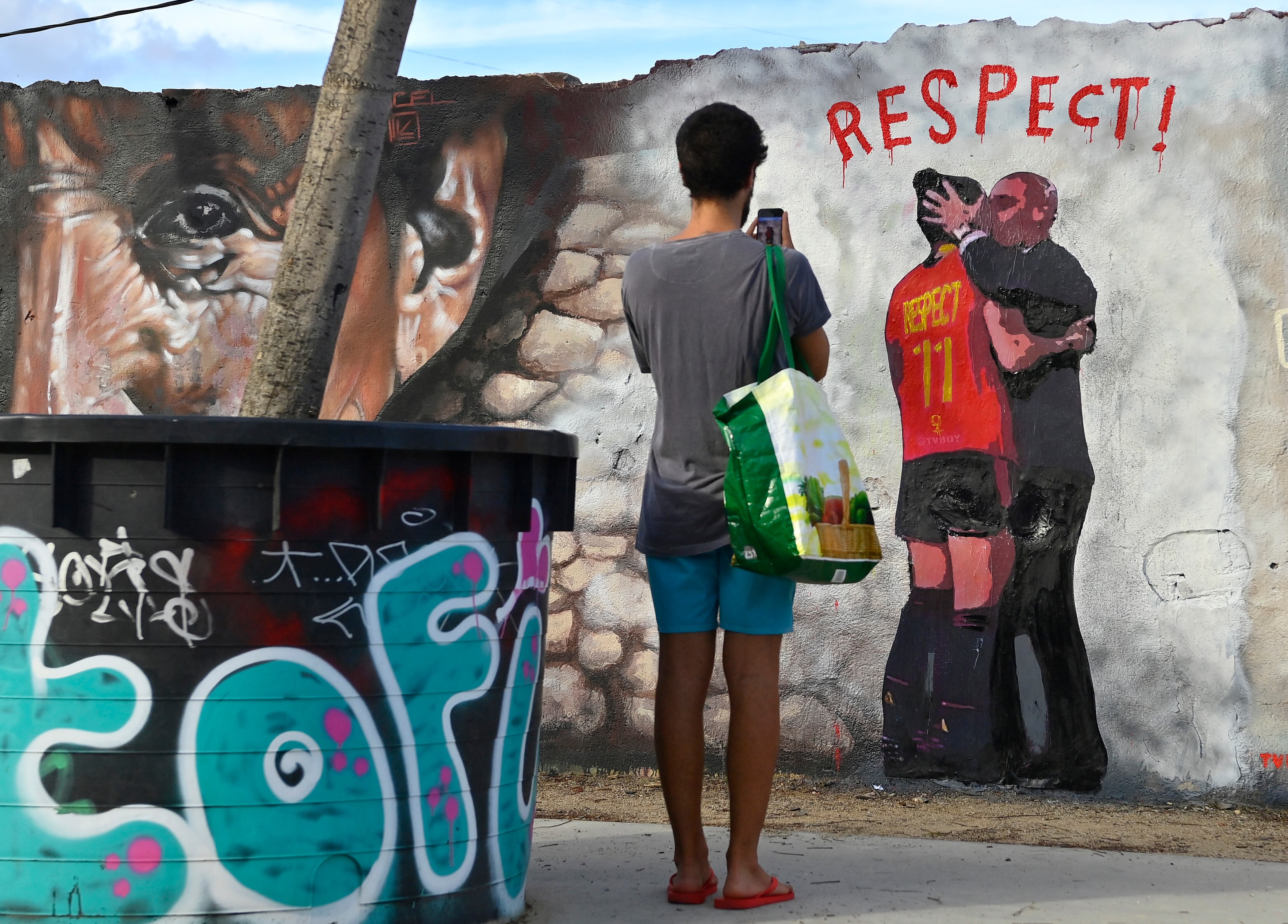 A man takes pictures of a mural by Italian street artist Salvatore Benintende aka TvBoy which depicts Spanish Football Federation President Luis Rubiales kissing Spain midfielder Jenni Hermoso, in Barcelona on September 1, 2023. Spain's sports court has agreed to investigate Luis Rubiales for forcibly kissing star player Jenni Hermoso, after the Women's World Cup final match in Sydney, paving the way for fresh sanctions against the scandal-hit football boss, sources close to the case said today. (Photo by Pau BARRENA / AFP) / RESTRICTED TO EDITORIAL USE - MANDATORY MENTION OF THE ARTIST UPON PUBLICATION - TO ILLUSTRATE THE EVENT AS SPECIFIED IN THE CAPTION