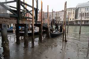 Los pasajeros se bajan de una góndola anclada a lo largo de un canal durante una marea baja en Venecia, Italia, el martes 21 de febrero de 2023. Algunos de los canales secundarios de Venecia prácticamente se han secado últimamente debido a un período prolongado de mareas bajas vinculado a una alta presión persistente. sistema meteorológico.