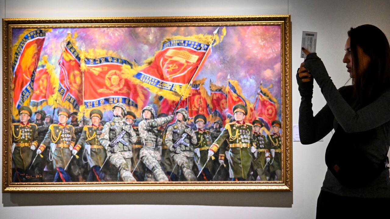 Un visitante se toma fotos frente a la pintura "Columna de desfile con gloriosas banderas militares" de Lee Gill Ho y Jang Ba Con durante la exposición de arte norcoreano en Moscú.
