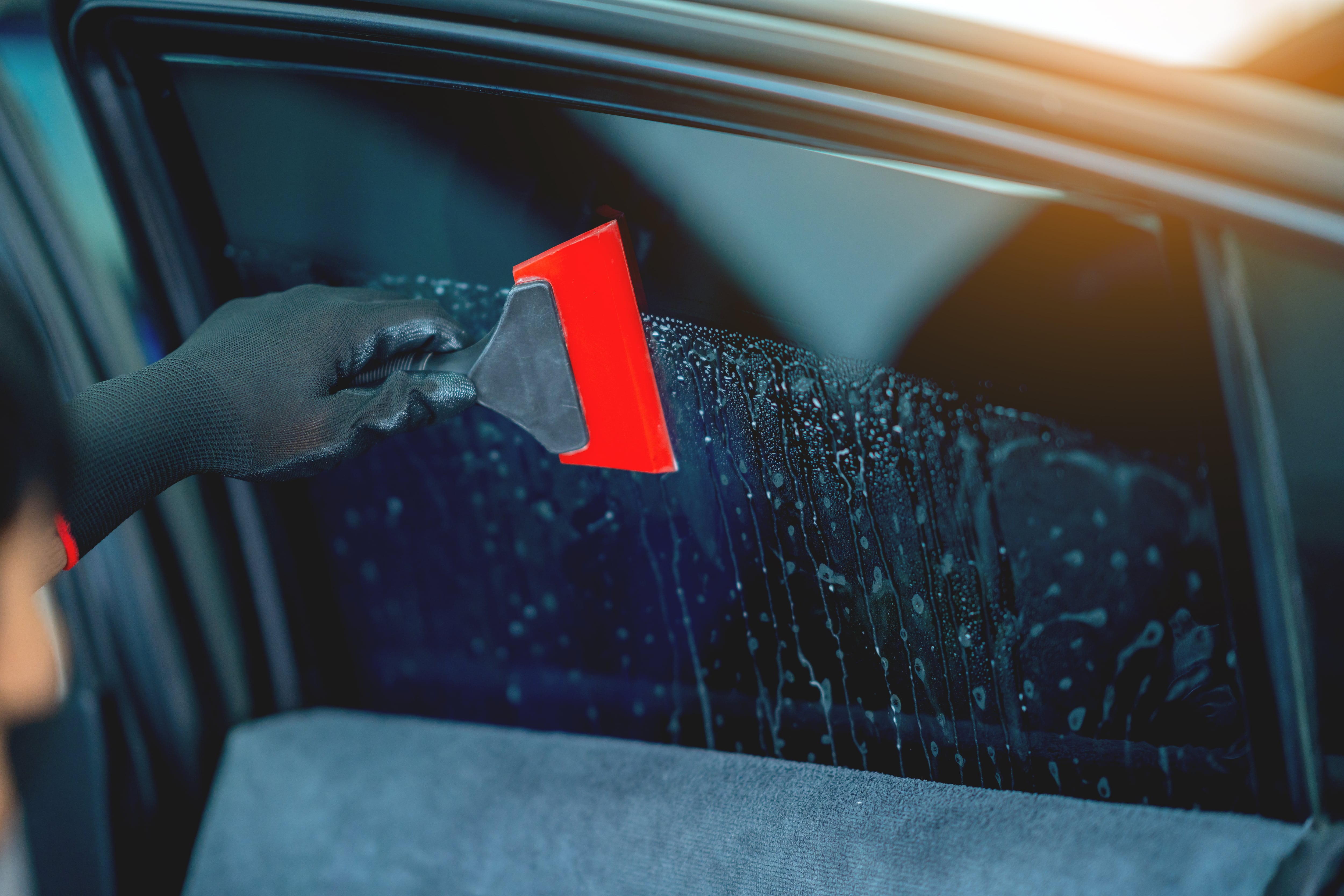 Technician uses equipment to install car window film.