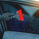 Technician uses equipment to install car window film.