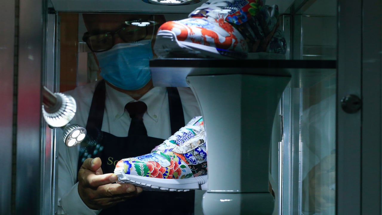 Un manipulador de arte de Sotheby's sostiene unas zapatillas de deporte únicas de Adidas y Meisse llamadas ZX8000 Porcelain, durante una vista previa en la casa de subastas de Sotheby's el 4 de diciembre de 2020 en la ciudad de Nueva York. Las zapatillas podrían alcanzar hasta un millón de dólares en una subasta, según Stheby's.