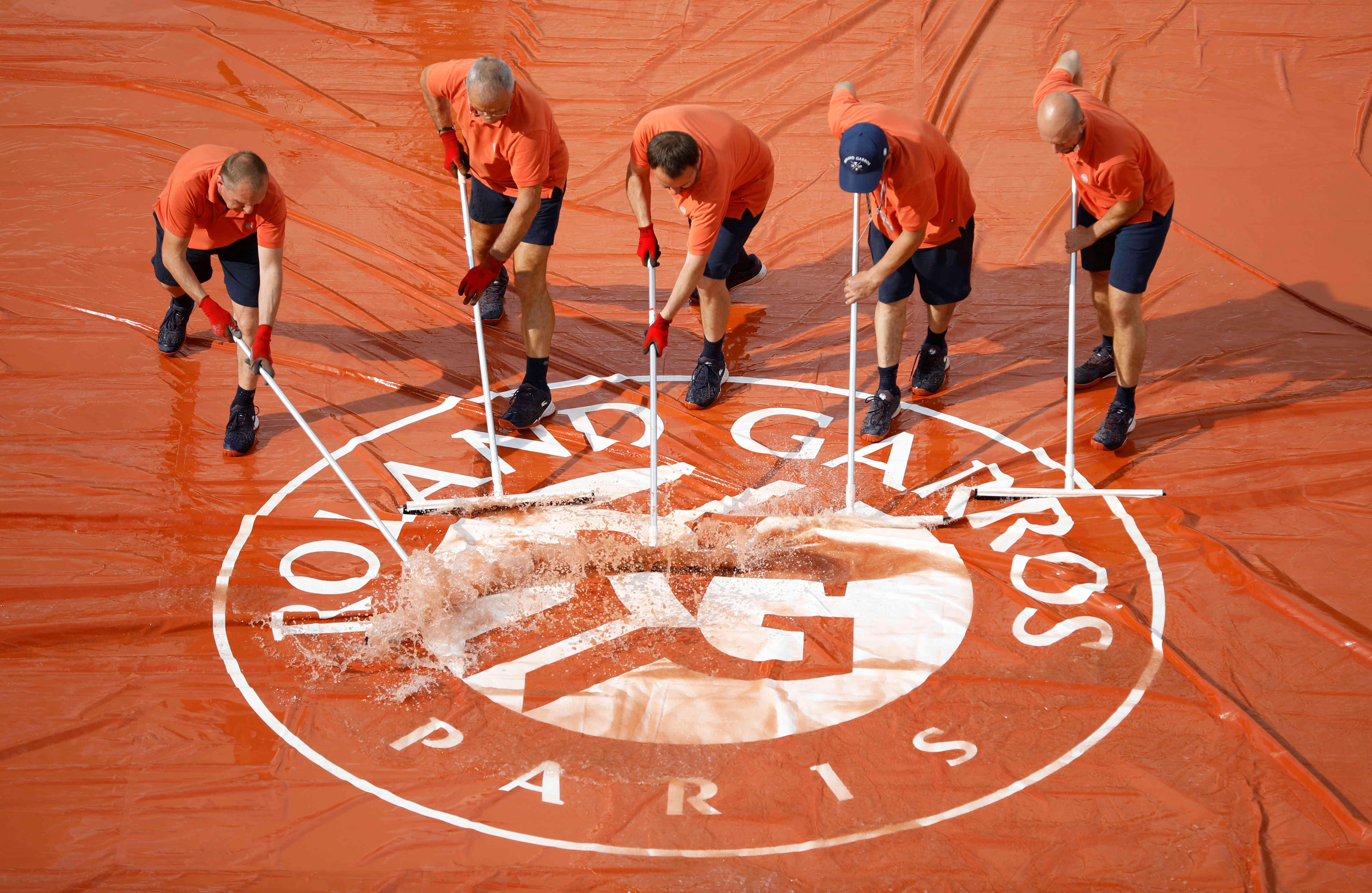 4 de junio - Trabajadores remueven agua de la cubierta de la cancha de polvo de ladrillo del Roland Garros en Francia. El partido de cuartos de final fue suspendido debido a las lluvias en Paris. FOTO: Jean-Francois Badias / AP