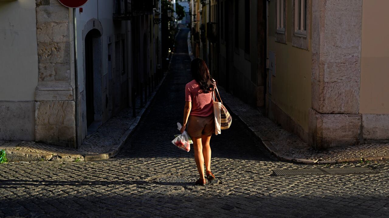 Una mujer camina por una calle mientras se pone el sol en Lisboa. (Foto AP / Armando Franca)