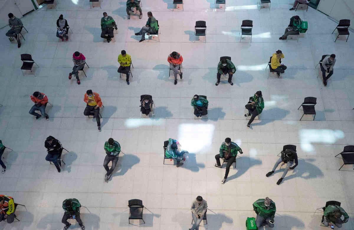 Las personas practican el distanciamiento social, mientras se sientan en sillas separadas, en una sala de espera de un puesto de comidas de en un centro comercial, con la esperanza de prevenir la propagación del coronavirus en Bangkok, Tailandia, el 24 de marzo. Foto: Sakchai Lalit/ AP. 