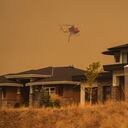 Un helicóptero equipado para responder a incendios forestales sobrevuela casas en el vecindario de Wilden cerca de Knox Mountain después de que los oficiales de la RCMP aplicaran una nueva orden de evacuación en Kelowna, Columbia Británica, el viernes 18 de agosto de 2023. (Darryl Dyck/The Canadian Press vía AP)