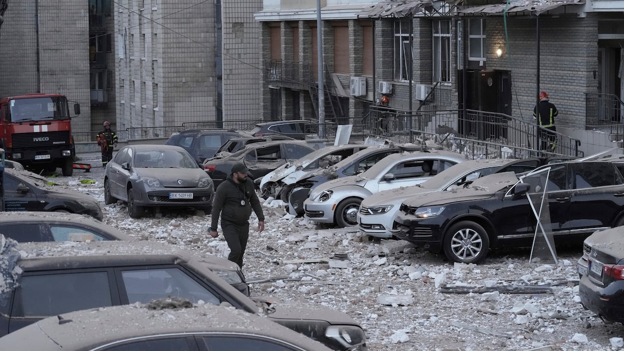 Un agente de policía camina por un estacionamiento con autos dañados, frente a un edificio de varias plantas, luego de un ataque ruso sobre Kiev, en Ucrania, el 30 de mayo de 2023. (AP Foto/Roman Hrytsyna)