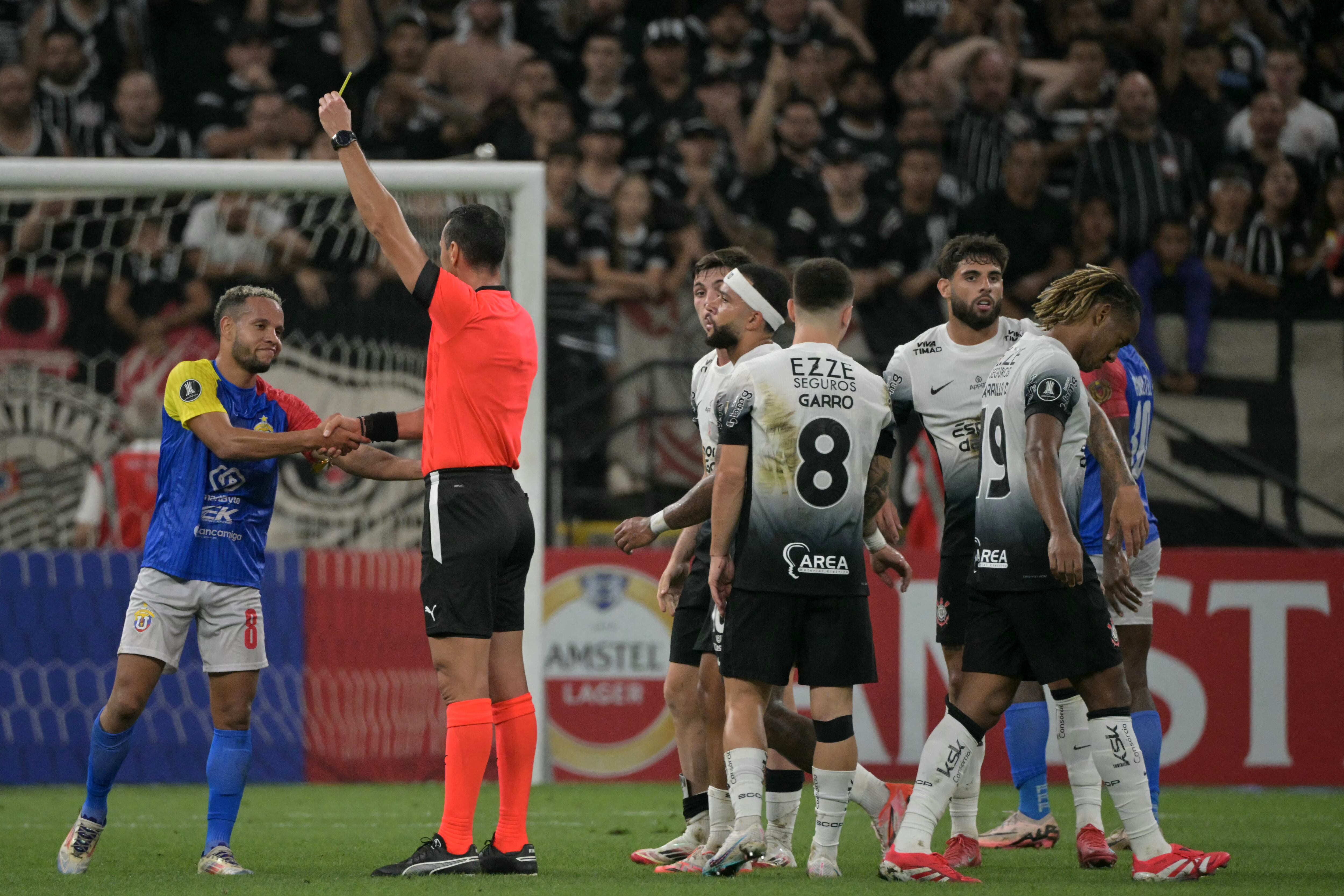 El árbitro colombiano Wilmar Roldán muestra una tarjeta amarilla al delantero colombiano de Universidad Central #08 Juan Zapata durante el partido de fútbol de vuelta de la segunda ronda de clasificación para la Copa Libertadores entre Corinthians de Brasil y Universidad Central de Venezuela en el estadio Neo Quimica Arena en São Paulo, Brasil, el 26 de febrero de 2025.