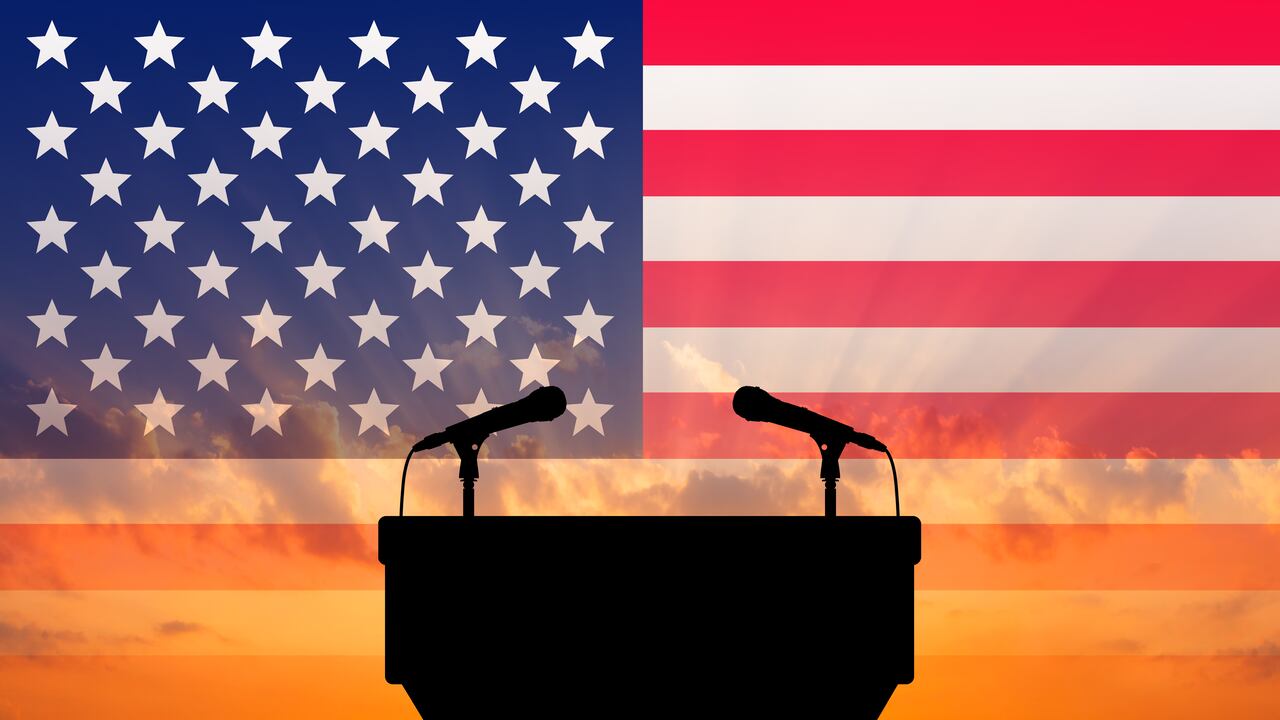 Podio con micrófono sobre el fondo de la bandera de Estados Unidos.